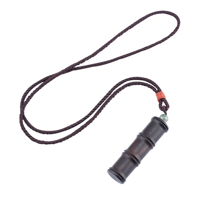 Ebony Wood Bamboo Prayer Box Necklace – Dark brown bamboo pendant with three raised rings on cord with orange knot and green bead, white background diagonal