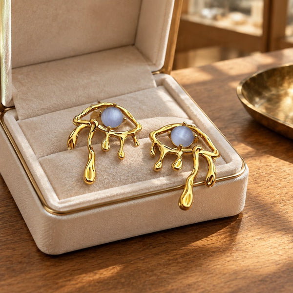 Gold Blue Cat's Eye Drip Earrings - Earrings presented on a surface with soft lighting, gift display