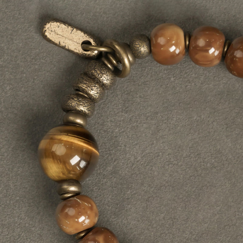 Tiger Eye Obsidian Wealth Bracelet – Close-up of brown ceramic beads with tiger's eye stone and weathered brass tag charm detail