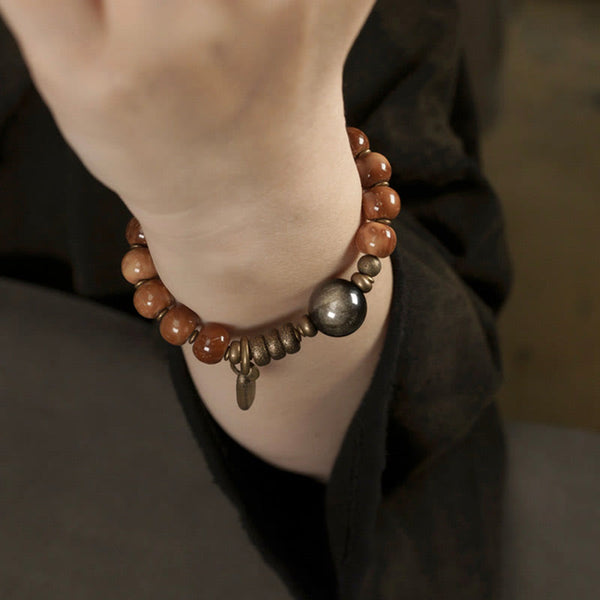 Brown beaded bracelet with dark focal bead worn on wrist