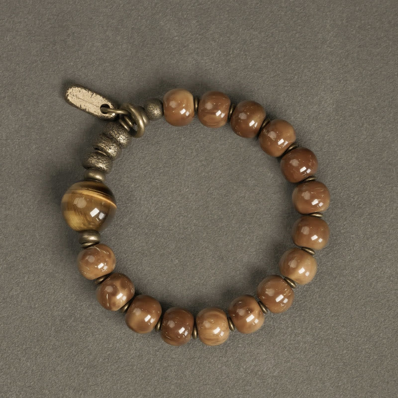 Tiger Eye Obsidian Wealth Bracelet – Caramel-brown beads with large tiger's eye stone and vintage brass toggle clasp on gray surface