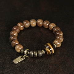 Tiger Eye Obsidian Wealth Bracelet – Warm brown wooden beads with tiger's eye centerpiece and brass spacers on dark textured background