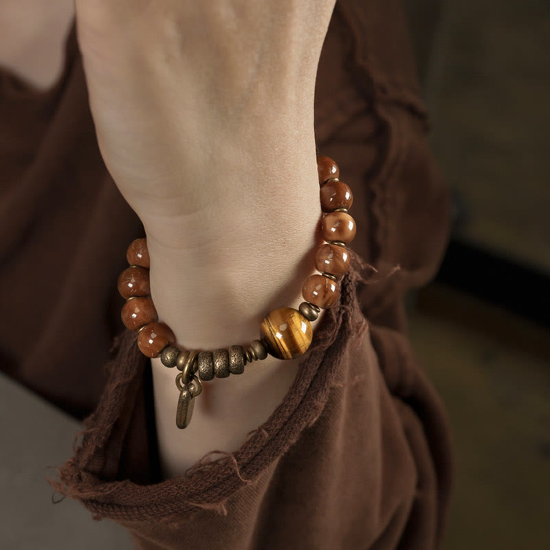 Tiger Eye Obsidian Wealth Bracelet – Brown stone beads with golden tiger's eye worn on wrist, bohemian lifestyle shot on brown fabric