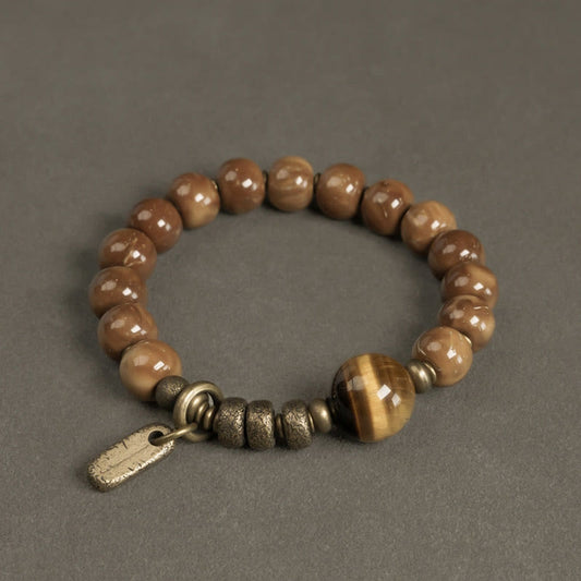 Tiger Eye Obsidian Wealth Bracelet – Polished brown beads with tiger's eye focal stone and brass spacers on gray textured surface