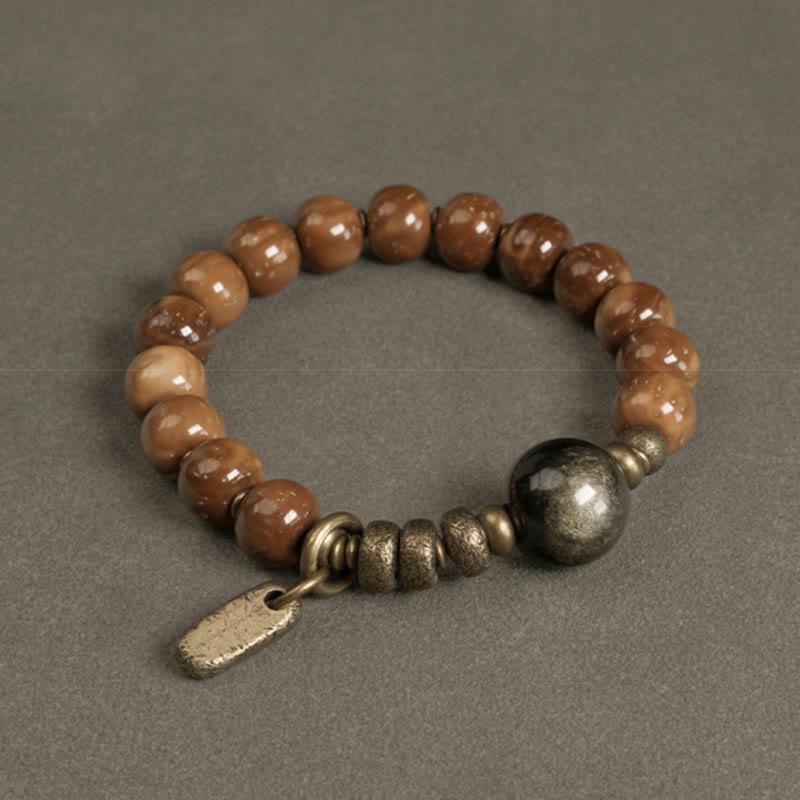 Tiger Eye Obsidian Wealth Bracelet – Honey-brown glazed beads with brass central sphere and tag charm on gray matte surface
