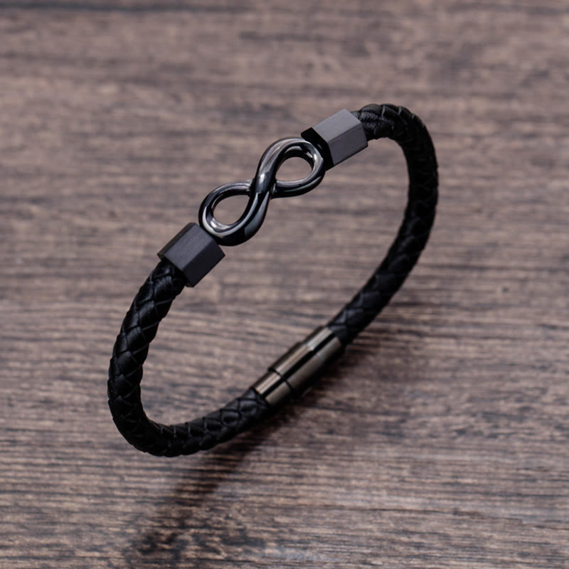 Endless Knot Titanium Steel Leather Bracelet – Gunmetal infinity bracelet on brown wood grain surface, slightly elevated three-quarter angle