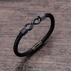 Endless Knot Titanium Steel Leather Bracelet – Gunmetal infinity bracelet on brown wood grain surface, slightly elevated three-quarter angle