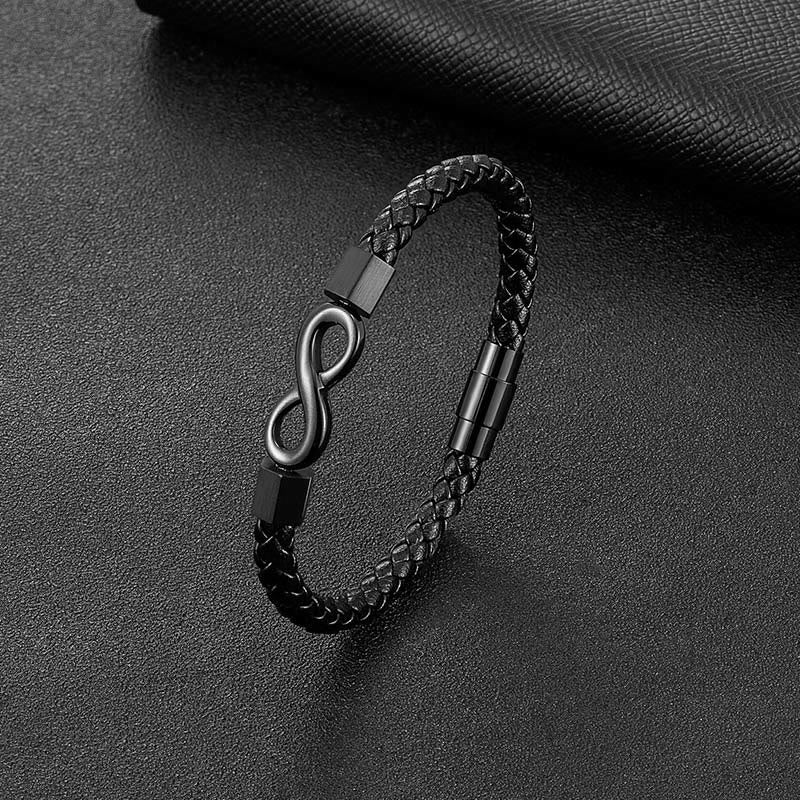 Endless Knot Titanium Steel Leather Bracelet – Black braided leather with matte infinity clasp on dark gray pebbled leather, elevated three-quarter angle