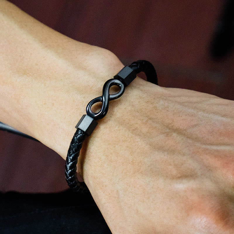 Endless Knot Titanium Steel Leather Bracelet – Black leather infinity bracelet worn on wrist, dark reddish-brown blurred background, side angle lifestyle
