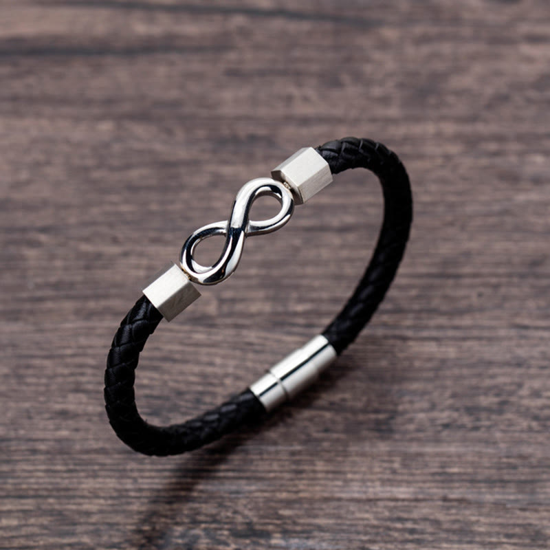 Endless Knot Titanium Steel Leather Bracelet – Silver infinity clasp on black leather with hexagonal beads and magnetic closure, brown wood grain background