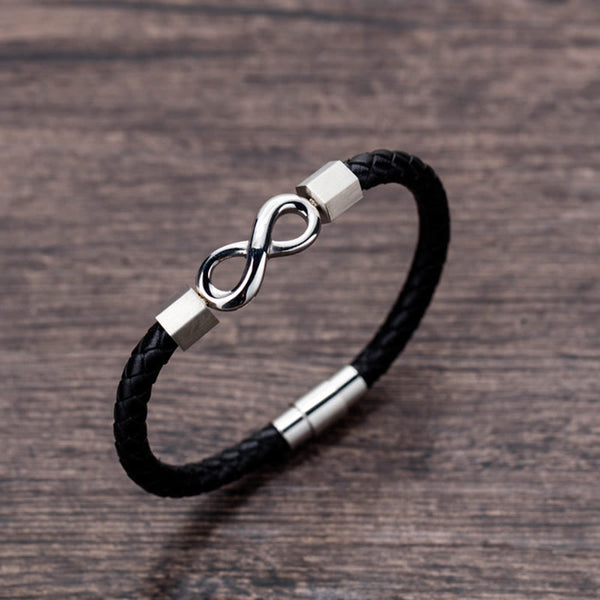 Endless Knot Titanium Steel Leather Bracelet – Silver infinity clasp on black leather with hexagonal beads and magnetic closure, brown wood grain background