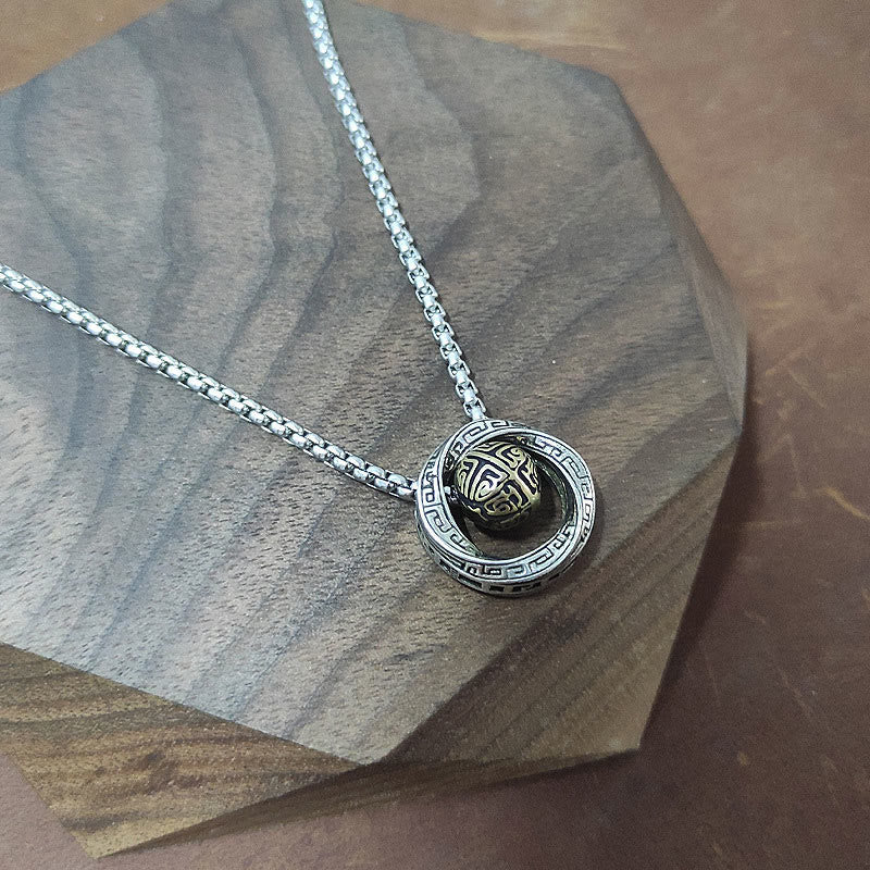 Mobius Copper Wealth Necklace – Silver Mobius pendant with gold sphere resting on dark octagonal wood display, warm brown leather background