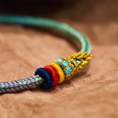 Five-Color Eight Thread Peace Knot Bracelet – Navy red yellow turquoise gold mesh wrapped bead and stacked ring knots transitioning to mint green cord, tan fabric macro