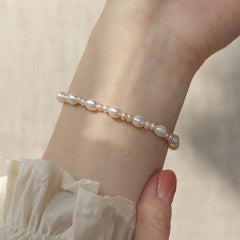 Natural Pearl Sincerity Bracelet – White pearl bracelet with silver chain link detail and gold leaf pendant close-up, pink floral fabric background