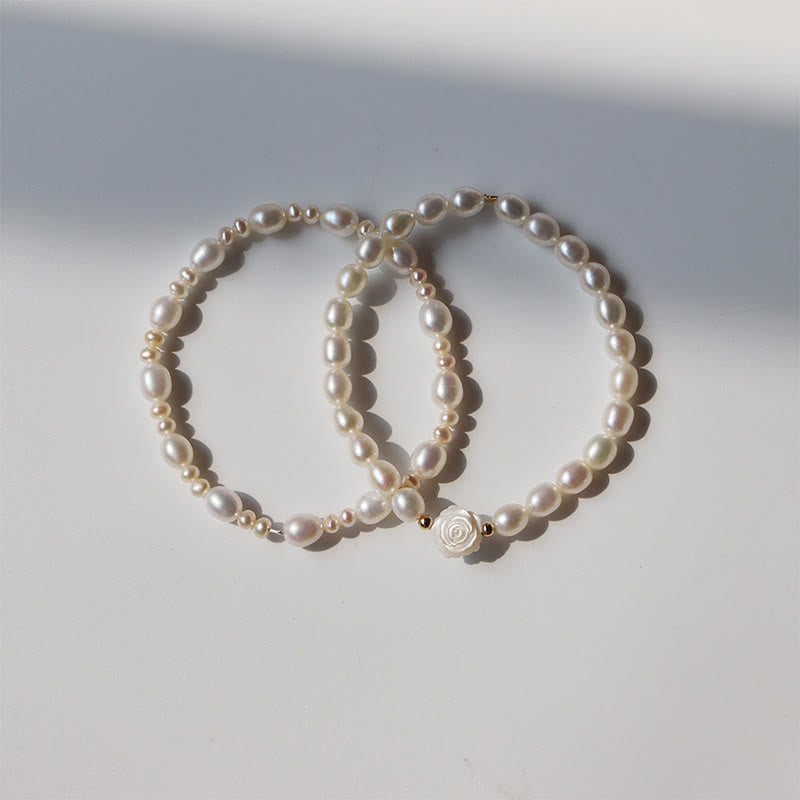 Natural Pearl Sincerity Bracelet – White pearl bracelet with gold leaf accents and silver chain worn on wrist, pink cherry blossom background, side lifestyle