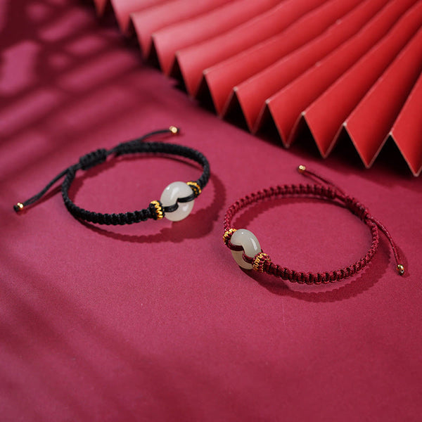 Peace Buckle Jade Abundance Bracelet – Two adjustable cord bracelets in black and burgundy with pale green jade ring pendants and gold beads, crimson fabric 45-degree