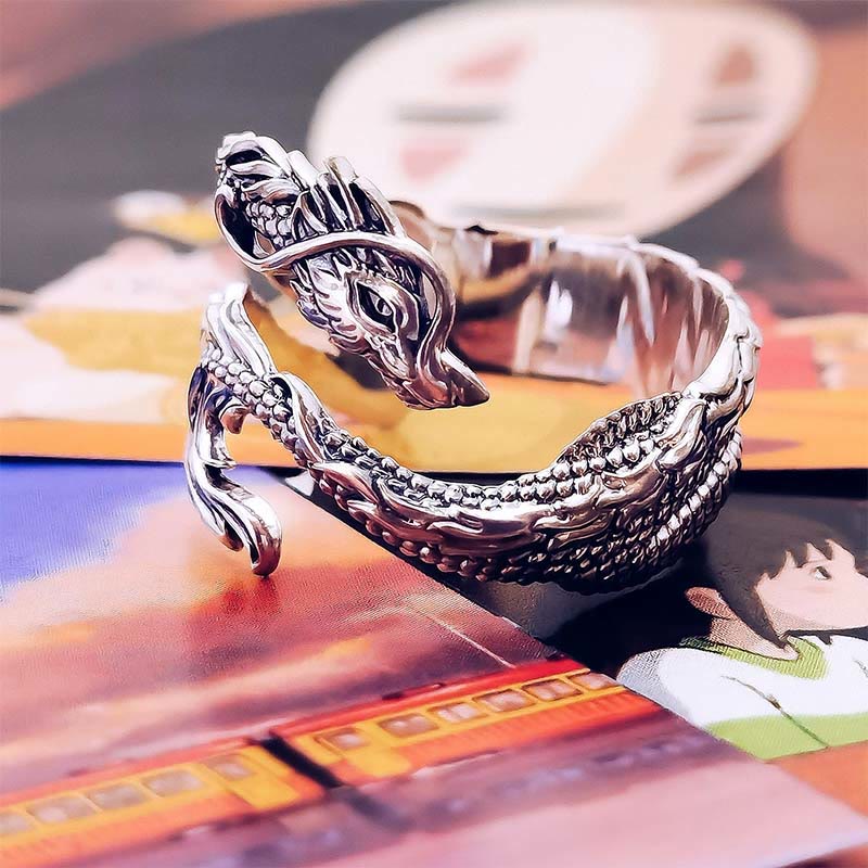 Vintage Dragon Pattern Silver Ring – Silver dragon cuff bracelet with scaled body and wing elements, anime-printed colorful background, low three-quarter angle