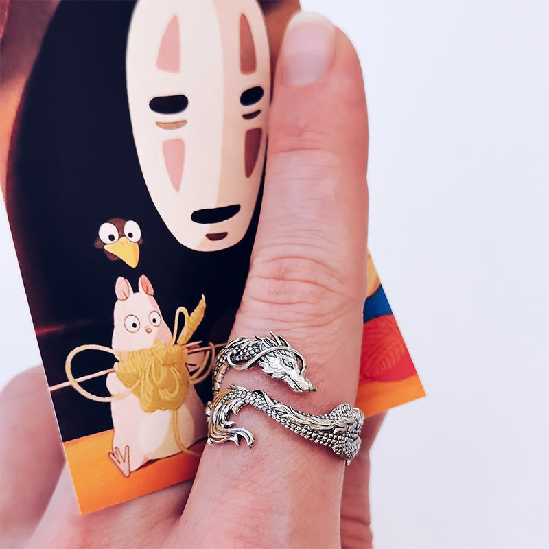 Vintage Dragon Pattern Silver Ring – Silver dragon wrap ring held between fingers against Studio Ghibli themed card, close-up side angle with soft lighting