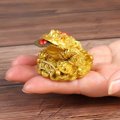 Golden Money Toad – small gold frog statue held in palm showing scale wooden table background, prosperity charm