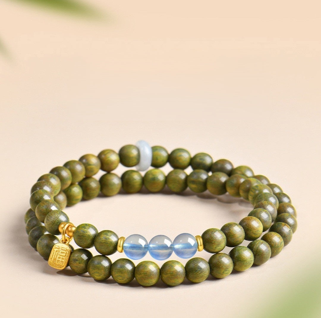 Green Sandalwood Bracelet – Double wrap with blue crystal and gold fortune charm on beige, natural wood