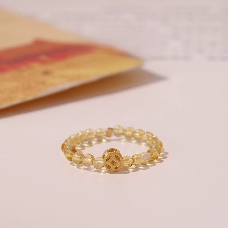 Citrine Coin Ring – Yellow citrine bead ring with gold Chinese coin charm on cream background, prosperity ring