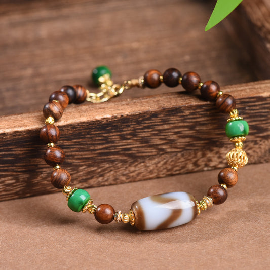 Dzi Rosewood Bracelet – Rosewood beads with Tibetan dzi centerpiece on wooden plank, green accent stones