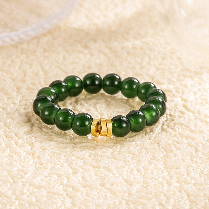 Jade Bead Ring – deep emerald green jade beads with gold clasp, warm cream textured backdrop, elegant gemstone band, silver jewelry