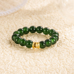 Jade Bead Ring – deep emerald green jade beads with gold clasp, warm cream textured backdrop, elegant gemstone band, silver jewelry