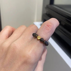 Agarwood Ring – dark wooden beads with gold coin charm worn on finger, indoor setting, feng shui jewelry