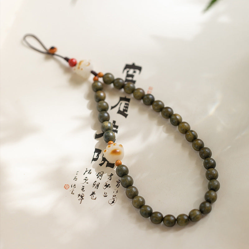 Sandalwood Cat Paw Charm – Green sandalwood bead strand with toasted cat paw charm on Chinese calligraphy paper, cultural phone accessory