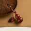 Sandalwood Gourd Keychain – reddish gourd with beaded tassels beside carved wooden plate