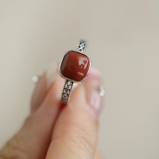 Red Agate Openwork Ring – square red agate sugar cube held between fingers on beige background, red agate ring
