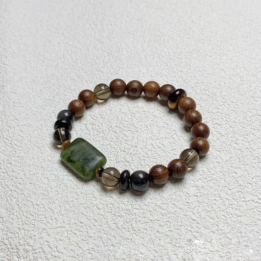 Sandalwood Wushi Bracelet – Sandalwood bead bracelet with green jade plaque and smoky quartz on white textured surface