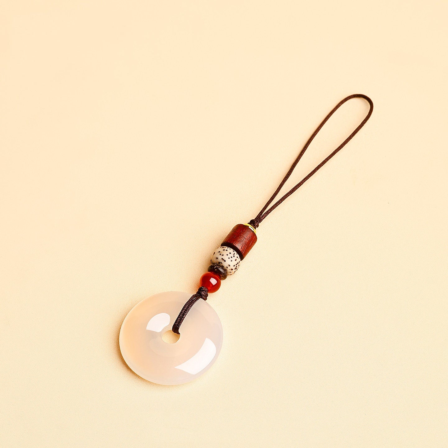 Jade Keychain Pendant – White jade donut with thin cord and bodhi beads on beige background, phone charm accessory