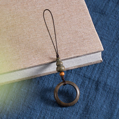 Sandalwood Phone Grip – Single green sandalwood ring lanyard with orange accent bead on book and blue cloth, wooden phone strap