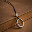Mantra Phone Ring – silver spinning ring with black cord on vintage brown book, engraved symbols