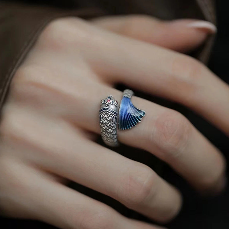 Enamel Carp Ring – silver carp head ring with vivid blue enamel tail on finger over dark background, silver carp ring