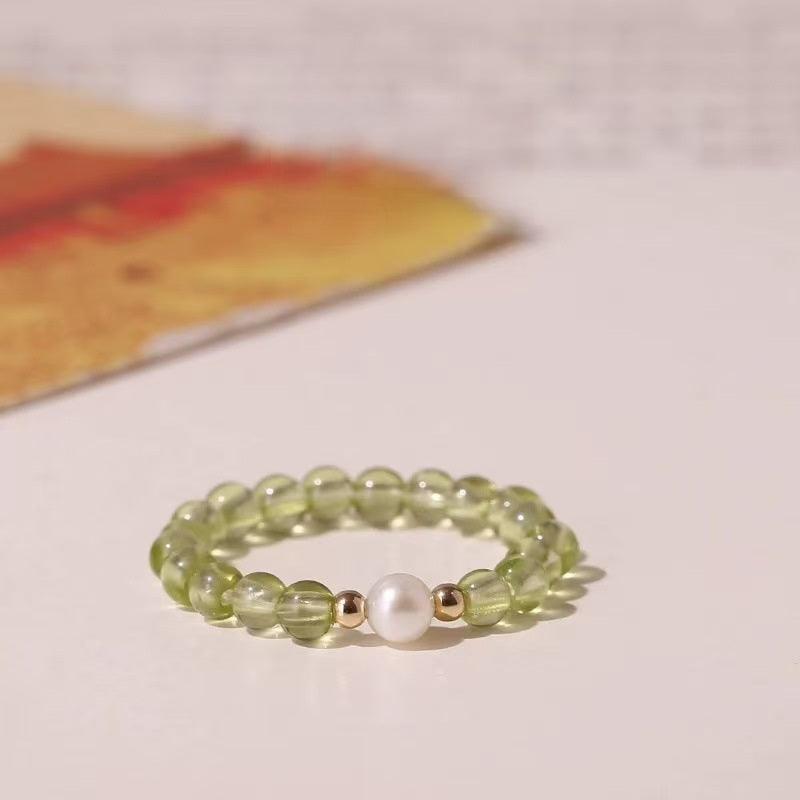 Peridot Pearl Ring – Green peridot bead ring with white pearl center and gold accents on light background