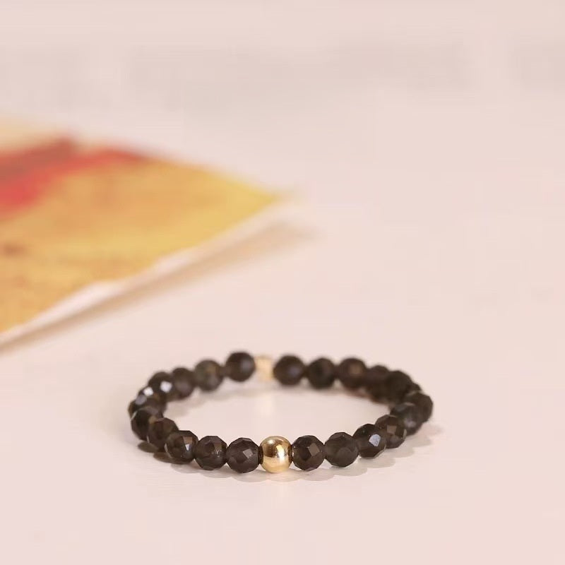 Black Spinel Ring – Faceted black spinel bead ring with gold center bead on light background, protection jewelry