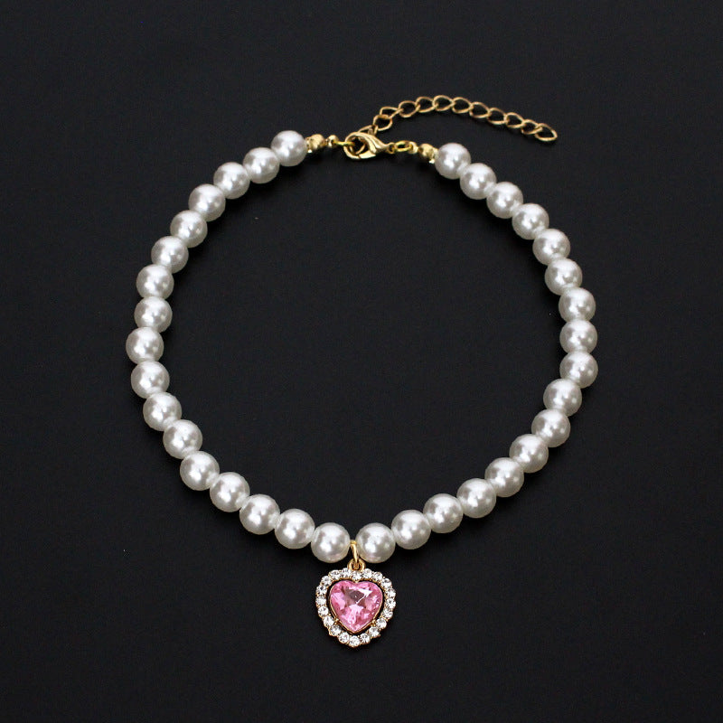Crystal Heart Pet Necklace – Pearl collar with pink heart crystal surrounded by rhinestones, black backdrop