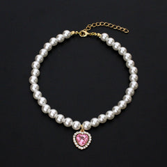 Crystal Heart Pet Necklace – Pearl collar with pink heart crystal surrounded by rhinestones, black backdrop