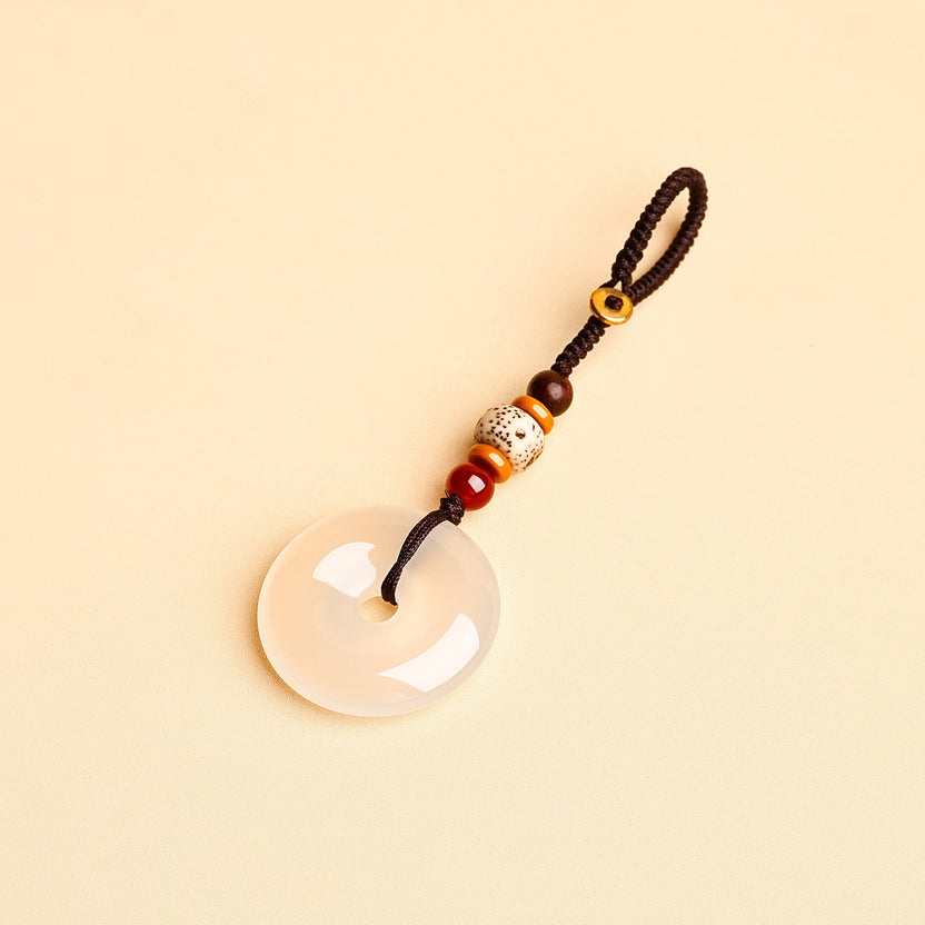 Jade Keychain Pendant – White jade donut pendant with braided rope and bodhi beads on beige background, feng shui Imagen principal del producto
