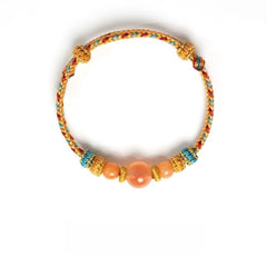 Dunhuang Agate Bracelet – golden braided cord bracelet with large peach moonstone center and blue knot details, fortune bracelet