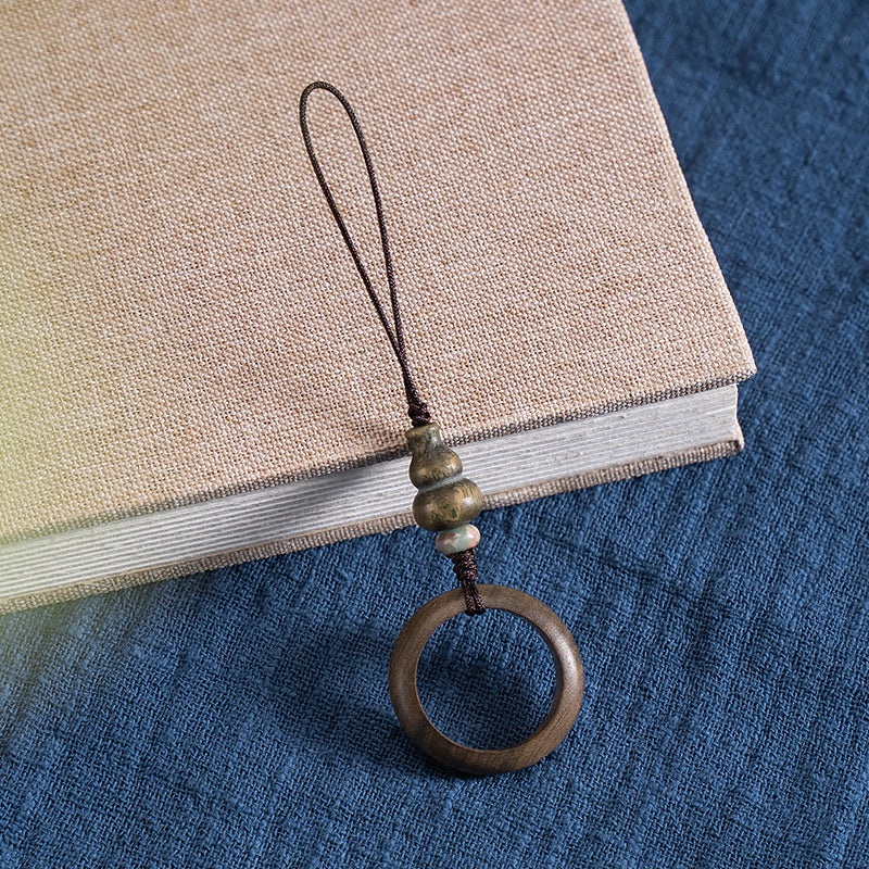 Sandalwood Phone Grip – Green sandalwood ring grip with golden hued gourd bead on beige book, Zen anti-drop accessory