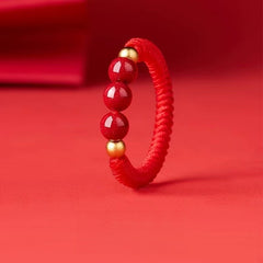 Cinnabar Cord Ring – Red braided cord ring with three red cinnabar beads and gold accents on red background