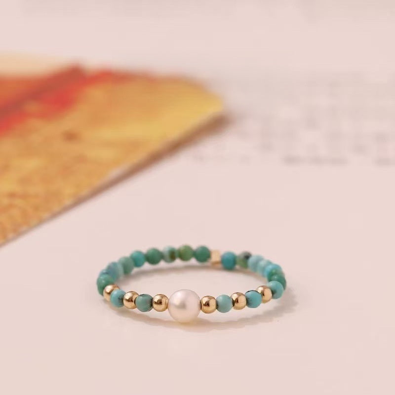 Turquoise Pearl Ring – Turquoise bead ring with white pearl center and gold beads on cream surface, boho ring