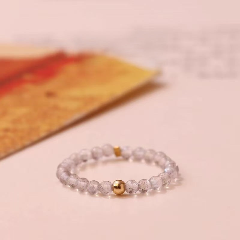 Labradorite Ring – Grey labradorite bead ring with gold center bead on soft pink background, intuition crystal ring
