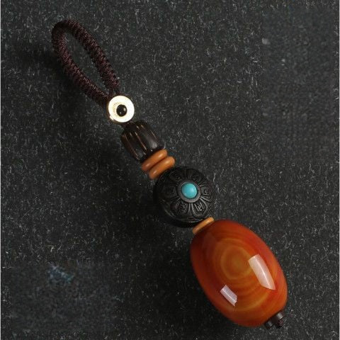 Red Agate Car Keychain – red agate barrel with carved ebony flower inlay on dark gray background, gemstone keychain