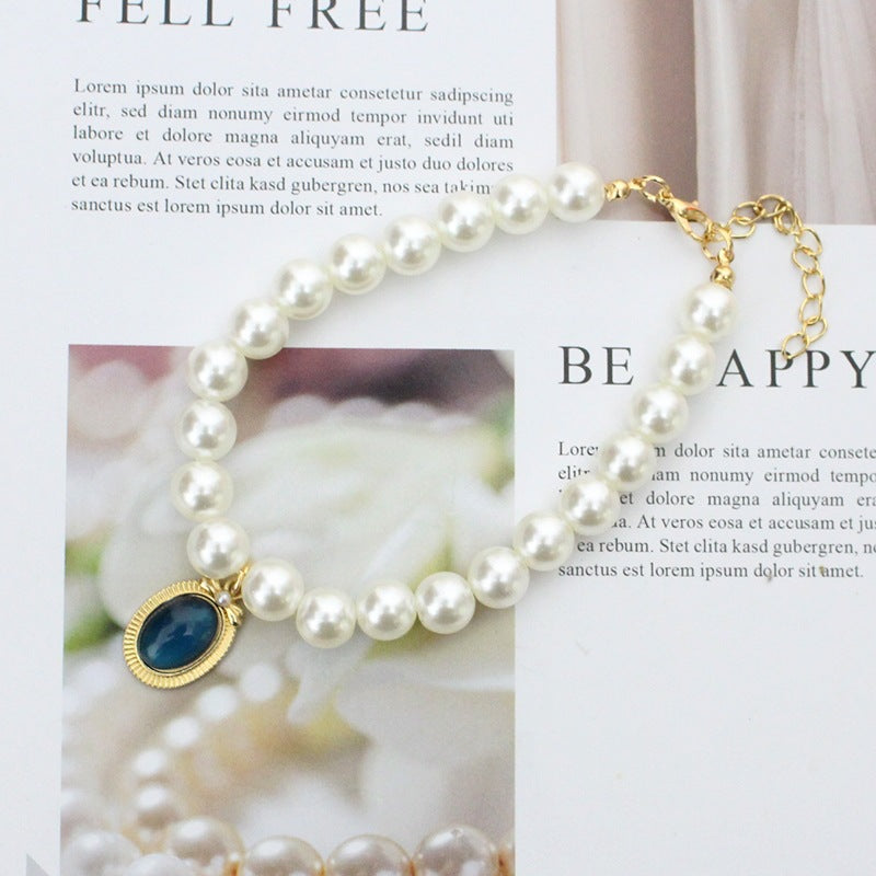 Pearl & Sapphire Pet Collar – Cream pearl strand with blue cabochon pendant, gold setting, elegant pet necklace