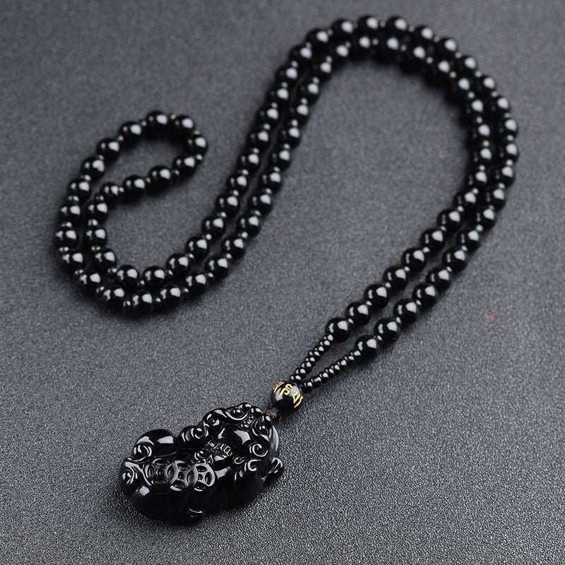Obsidian Pixiu Necklace – Black obsidian bead chain with carved pixiu pendant on gray, protection amulet